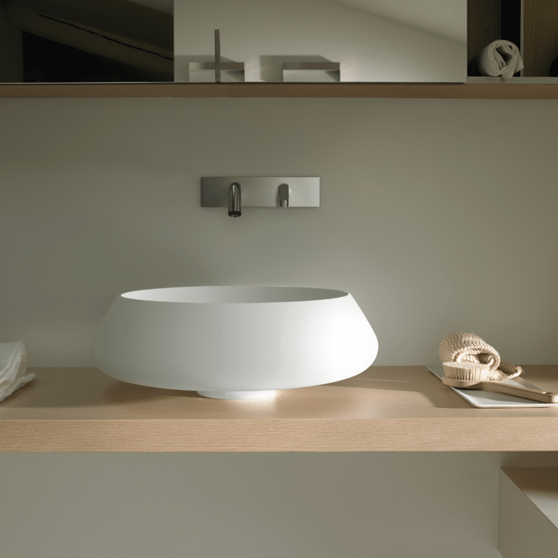 Bjhon 2 Waschbecken von Agape, Design Angelo Mangiarotti. Weißes Aufsatzwaschbecken auf Holzplatte mit Wandarmatur. Verfügbar in massivem Marmorblock, hochwertigem Cristalplant® oder Cemento.