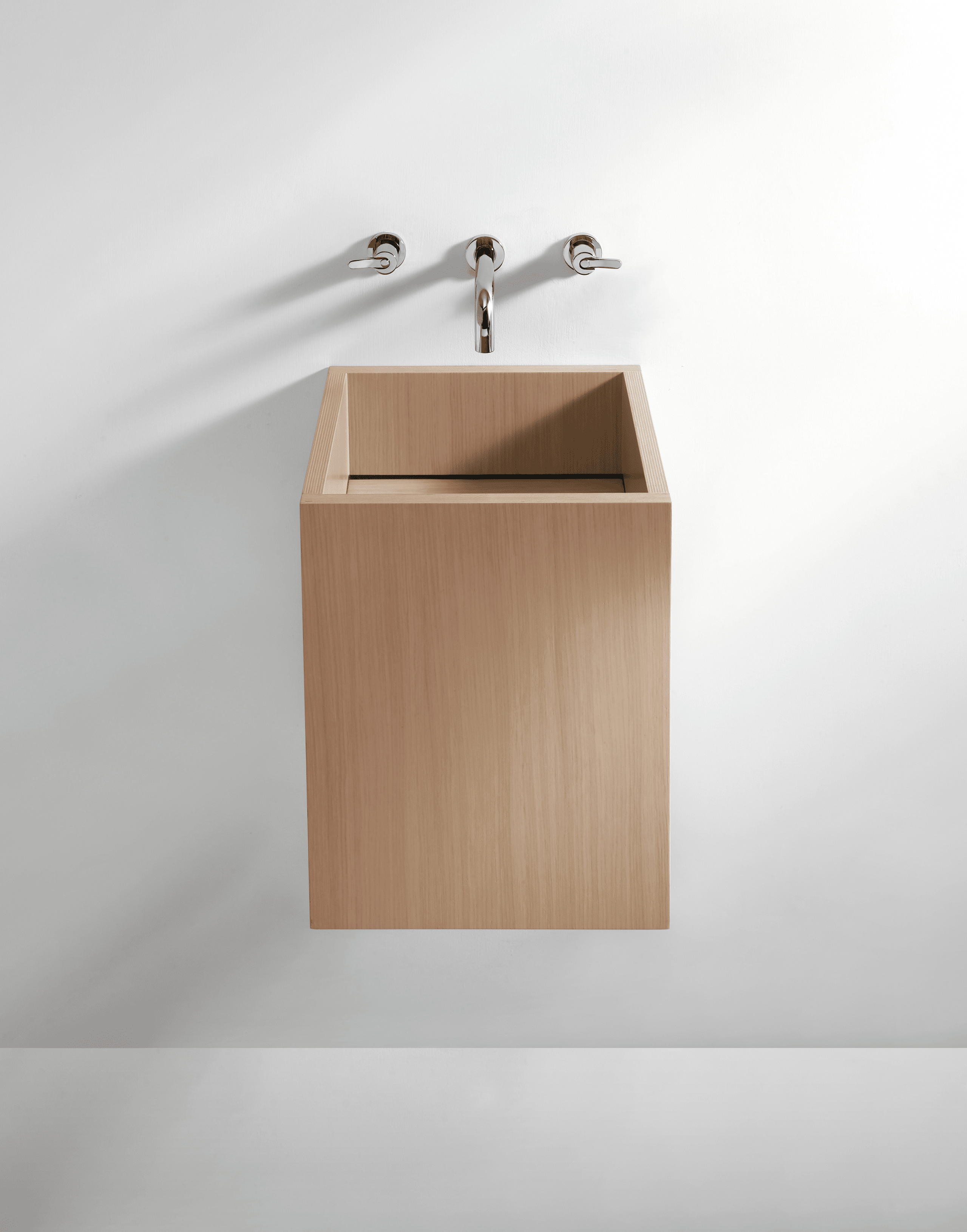 Agape Cube Waschbecken von Benedini Associati mit verchromter Wandarmatur, in hellem Holz an weißer Wand.