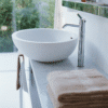 Agape Spoon XL Aufsatzwaschbecken, Detailansicht mit eleganter Chrom-Armatur auf einer Marmorplatte, definierend Luxus und Stil neu. Dieses Aufsatzwaschbecken ist verfügbar in weißem Cristalplant® biobased.