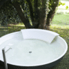 Outdoor Badewanne Ufo von Agape mit dunkelgrau lackierter Außenseite und weißer Cristalplant® Rückstütze, Design Benedini Associati, auf einer Rasenfläche unter einem Baum.