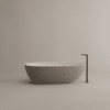 Freistehende Badewanne Spoon M von Agape in reinem Weiß aus Cristalplant biobased Mineralguss, Design Benedini Associati, mit schwarzem Hahn vor einem beigefarbenen Hintergrund.